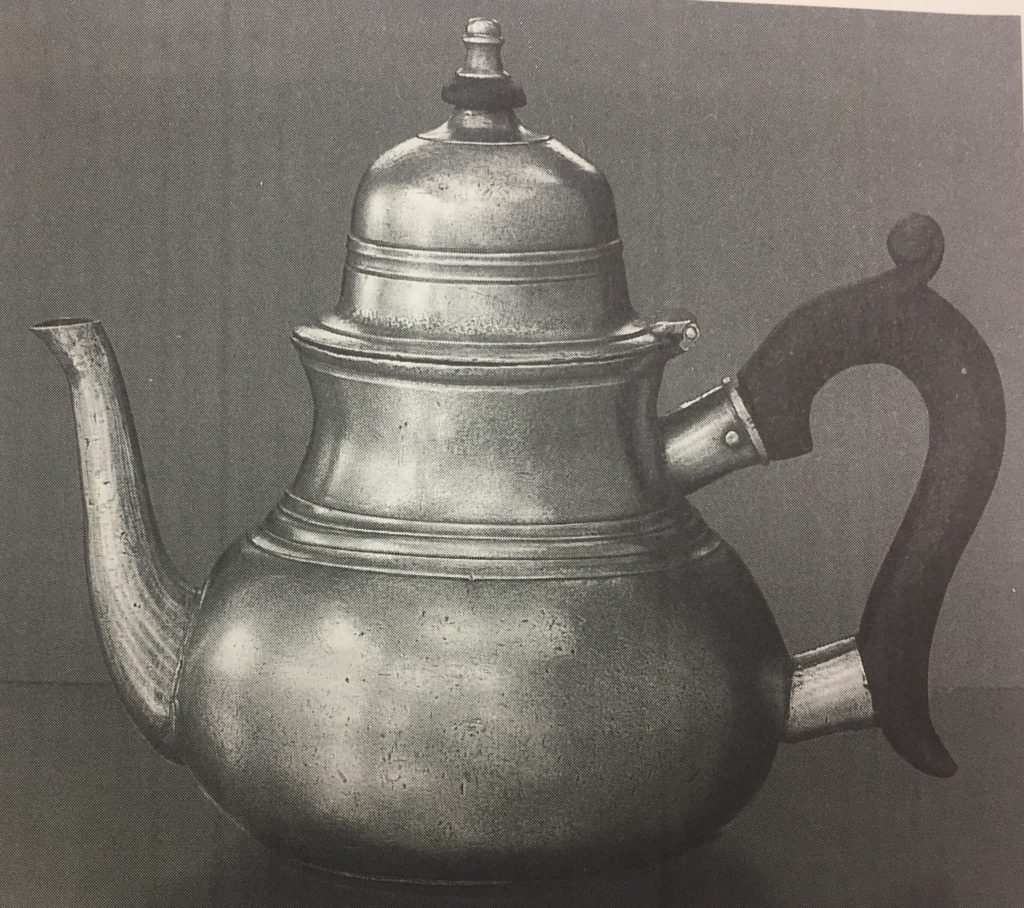 A small pewter teapot seen from the side